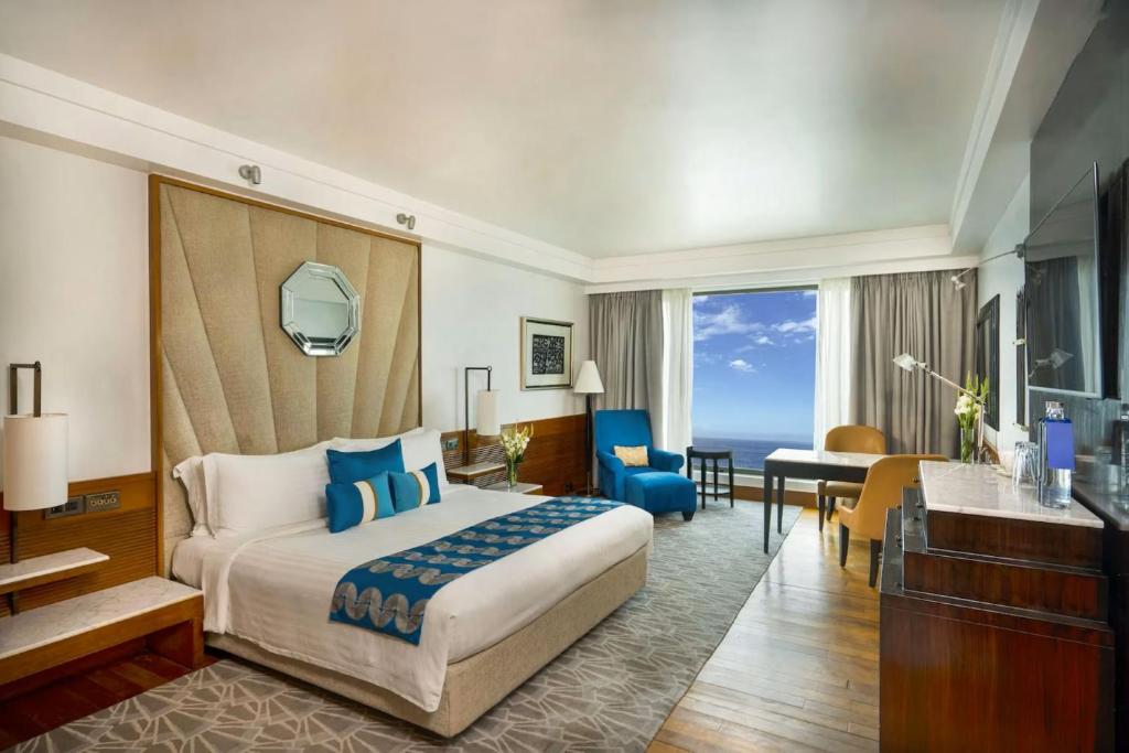 a hotel room with a large bed and a desk at Hotel DSR Krone New Delhi in New Delhi