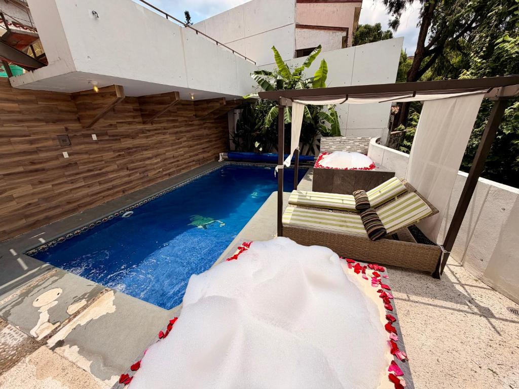 a swimming pool with a chair and an umbrella at Loft Lujo Estilo y Diseño, alberca con calefacción! Cuernavaca somos los únicos en ofrecerte 2 jacuzzis tipo Spa con agua caliente y sistema de hidromasaje, elegante y amplia cama de alberca, 3 Smart TV, terraza privada con asador de carbon, WiFi gratis! in Cuernavaca