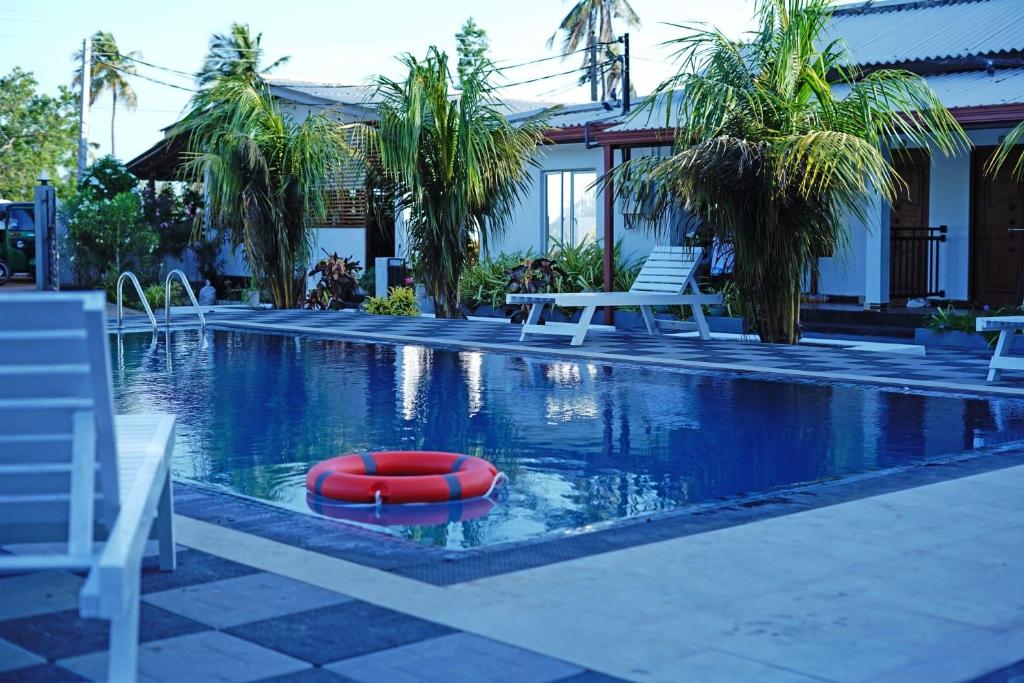 a swimming pool with a red float in the water at Coconut Leaf Shadow Guest in Nilaveli
