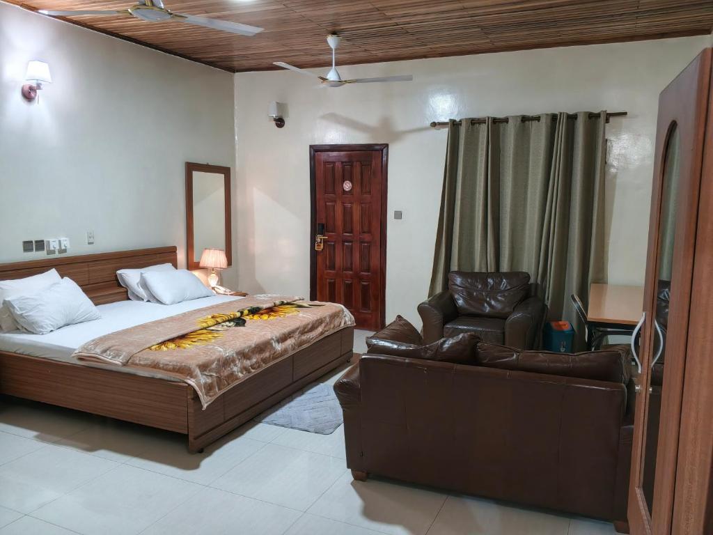 a bedroom with a bed and a couch and a chair at Royal Irenic Hotel in Madina