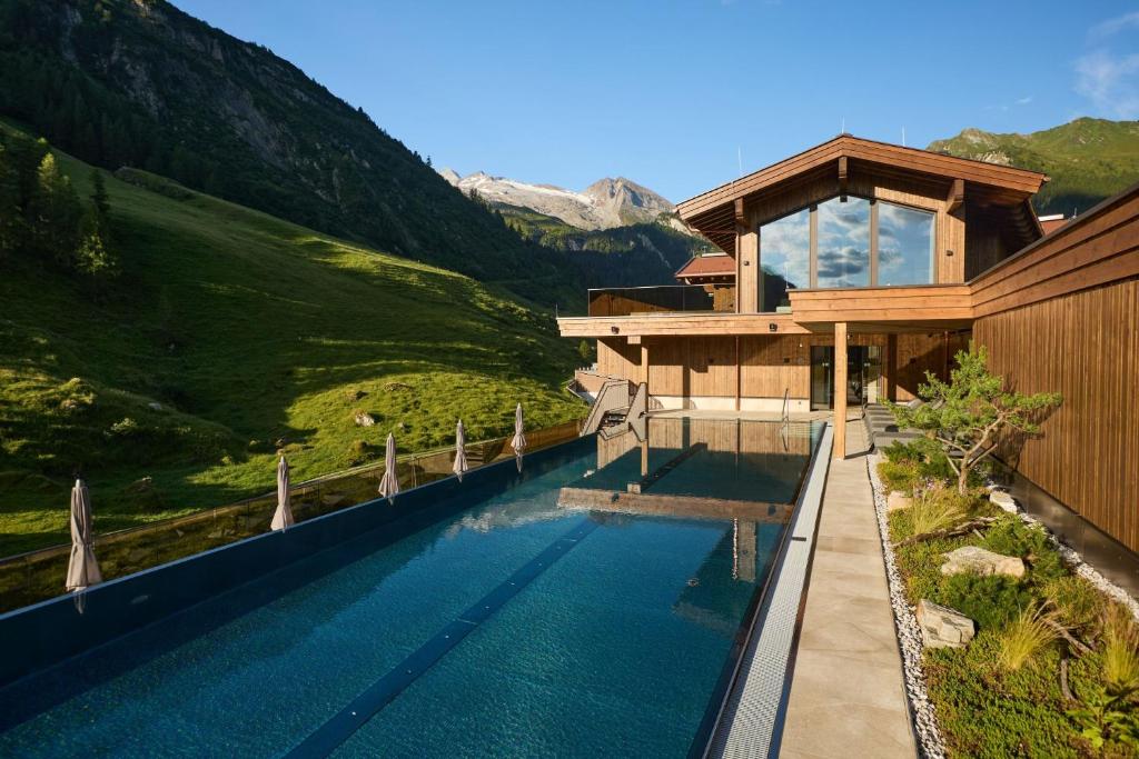 a house with a swimming pool next to a mountain at Hotel Alpenhof in Tux