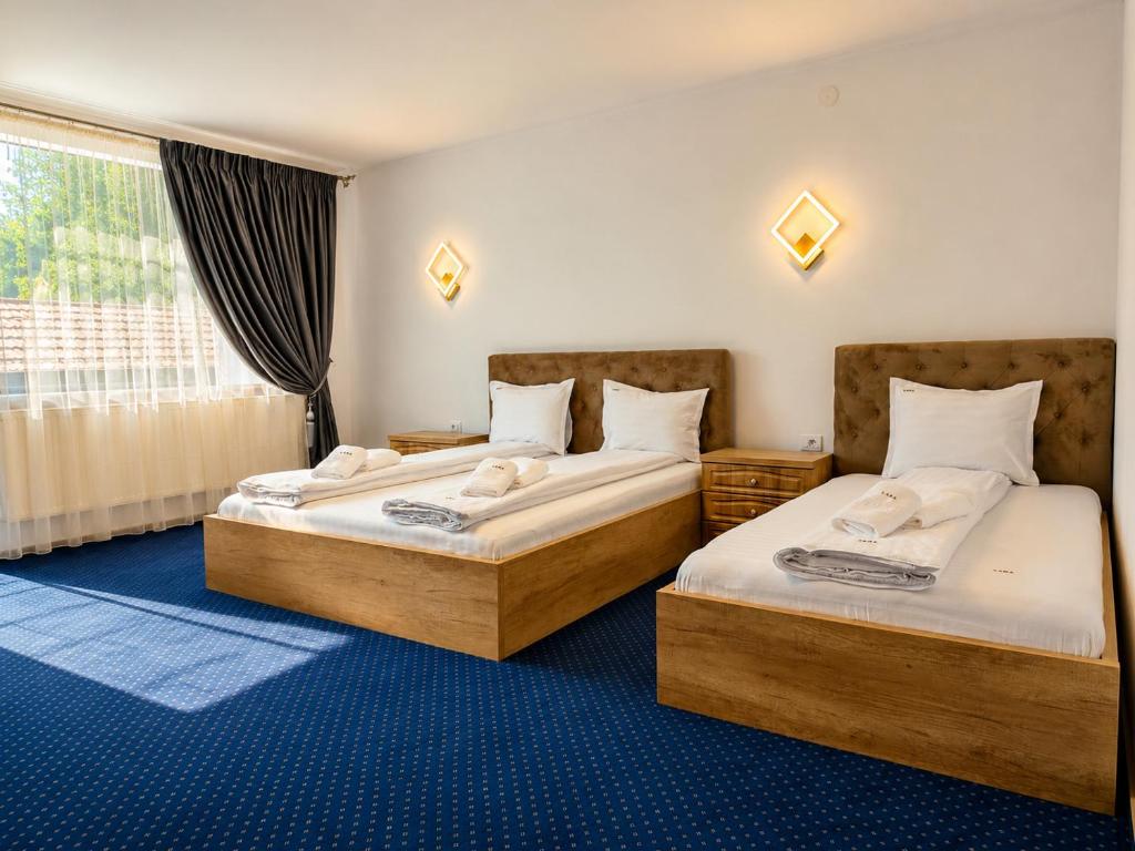 two beds in a room with a window at Pensiunea Lara in Râşnov