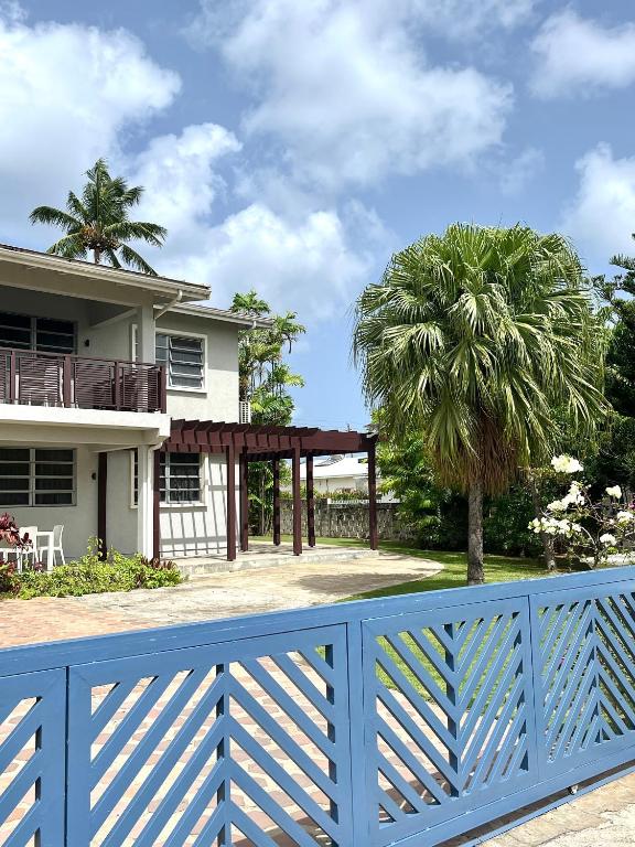 a blue fence in front of a house with a palm tree at Brightridge Condos in Bridgetown