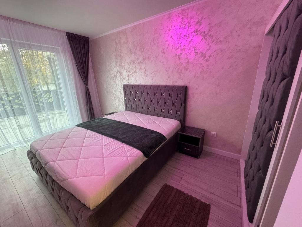 a pink bedroom with a bed and a window at Apartament White Tower in Ploieşti