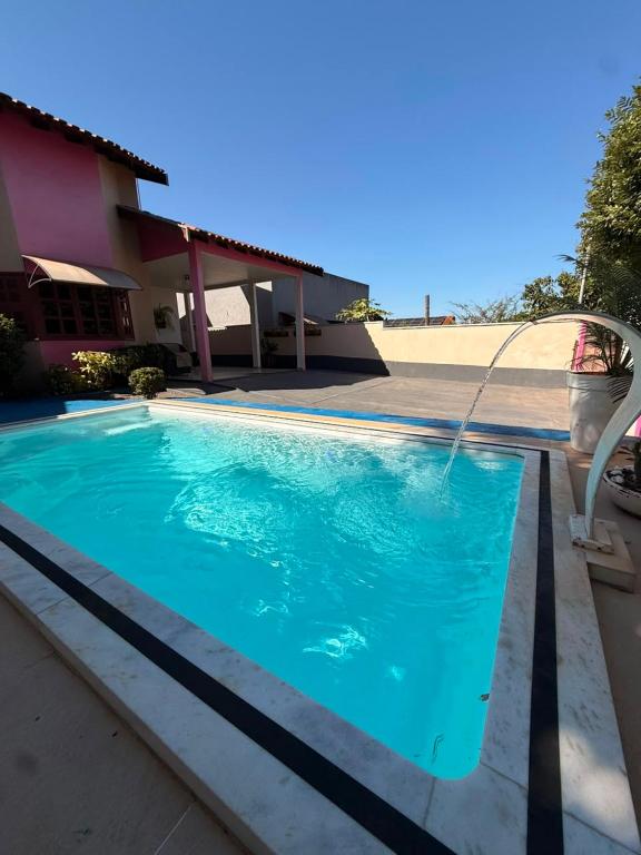 a swimming pool with a water hose in front of a house at Casa de Temporada Ipê Rosa in Bonito