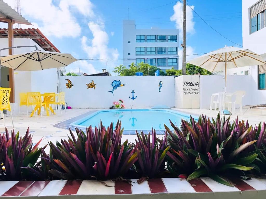 a swimming pool with plants and umbrellas at Pousada Sal e Mar Maracaipe in Porto De Galinhas