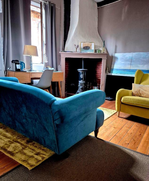 a living room with a blue couch and a fireplace at Chambre d'hôtes Abbatiale in Bernay
