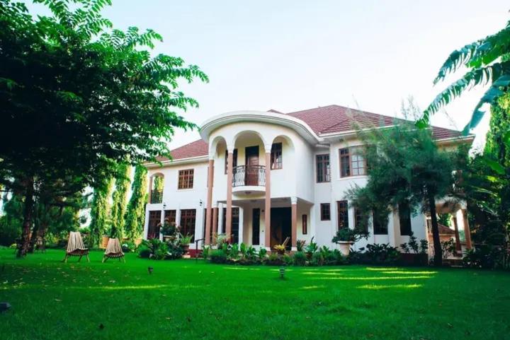 a large white house with a yard with green grass at Kilimanjaro pazuri summit villas 1 in Msaranga