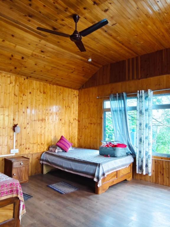a bedroom with a bed and a ceiling fan at Saamiyanaa Cloud Nest in Kalimpong