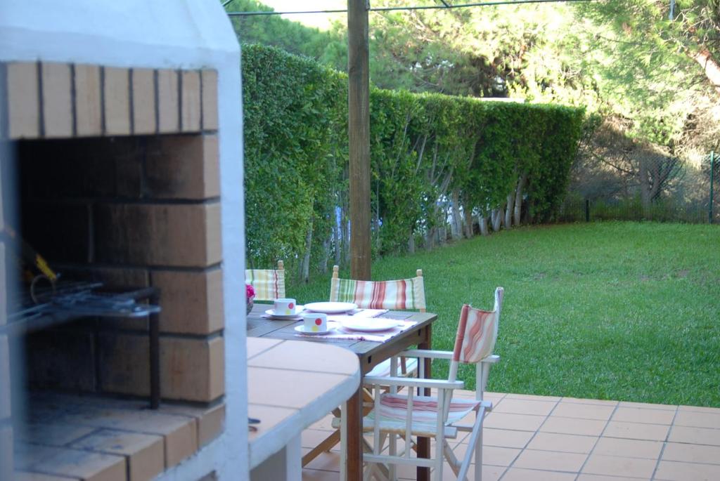 eine Terrasse mit einem Tisch, Stühlen und einem Kamin in der Unterkunft Praia Verde Residence in Praia Verde