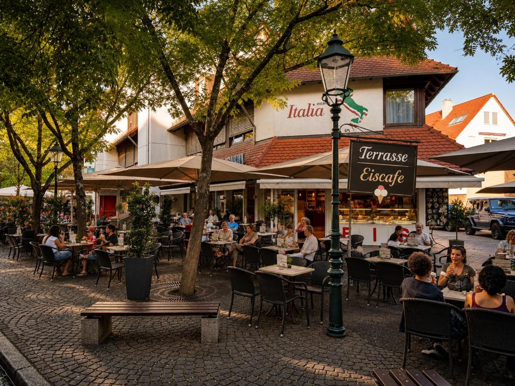 a group of people sitting at tables outside a restaurant at Hotel Garni Italia in Bühl