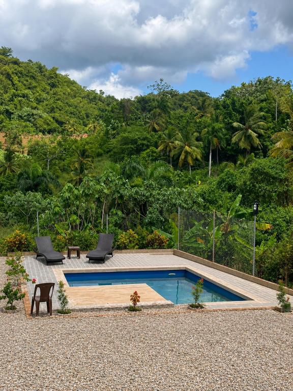 a swimming pool with two chairs and a table at Xamanai Playa Rincón III in Las Galeras