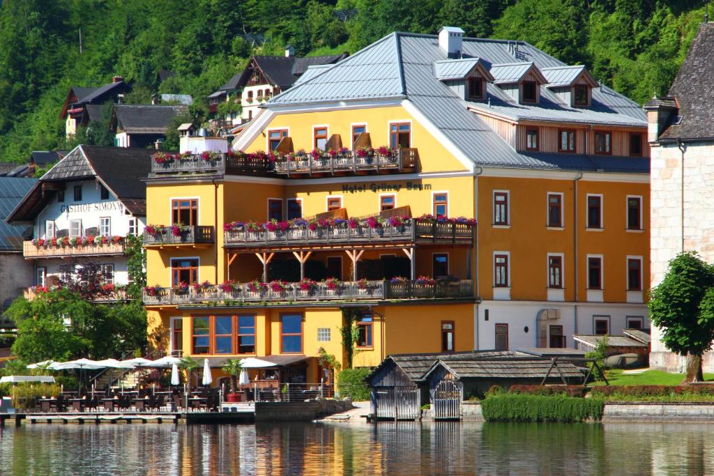 a yellow building with chairs on the balconies next to the water at Seehotel Grüner Baum in Hallstatt