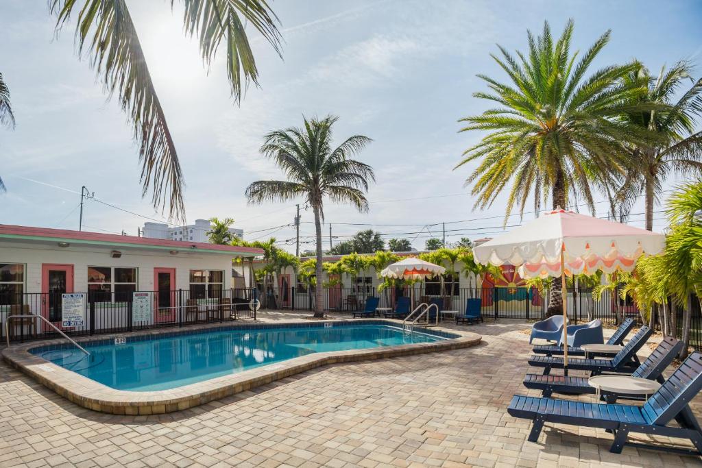 a resort pool with chairs and palm trees at Monaco Vacation Rentals in Clearwater Beach