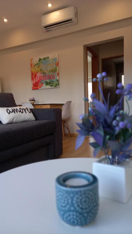a living room with a couch and a vase with blue flowers at Brisas Apart in Olavarría