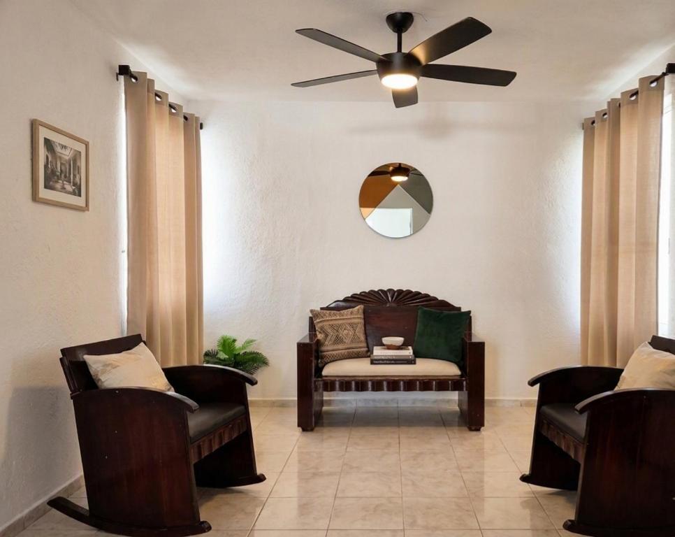 a living room with a ceiling fan and chairs at Casa San Pedro in Mérida