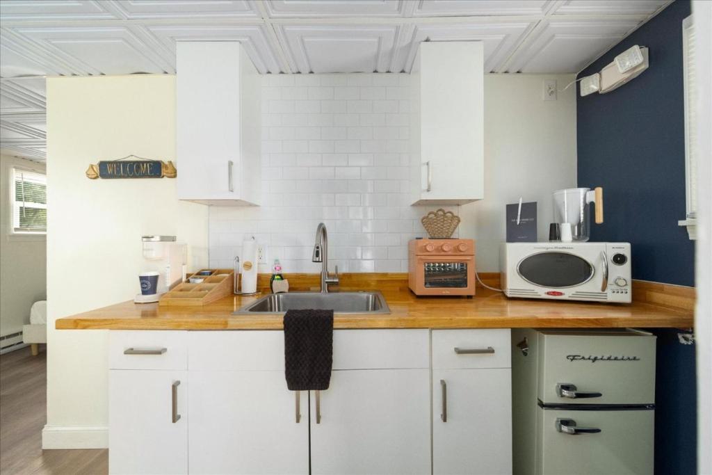 a kitchen with white cabinets and a sink and a microwave at The Beachside Co in Sylvan Beach