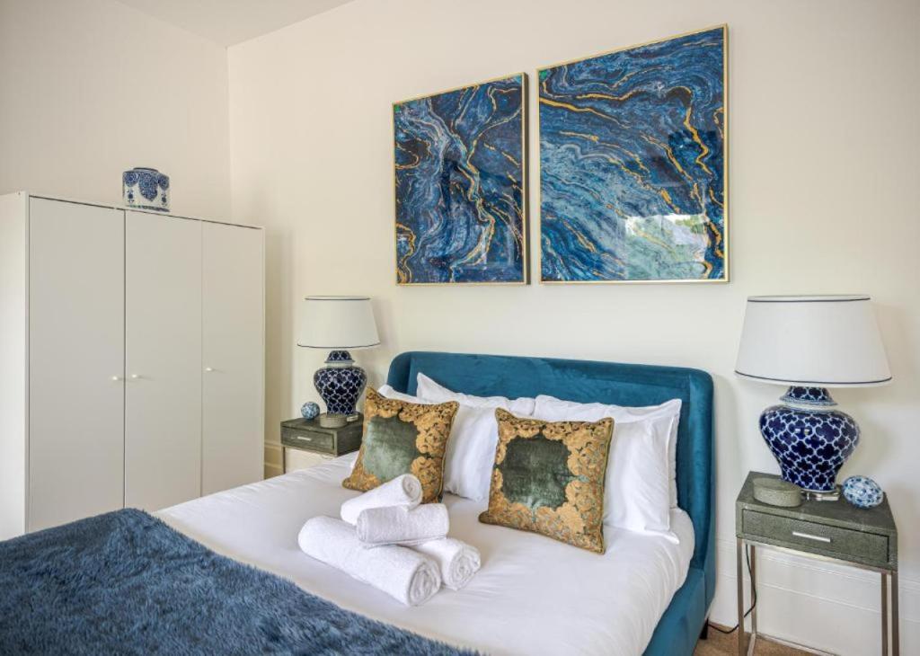 a bedroom with a blue bed with towels on it at Elegant 2BR Ground-Floor Teddington Flat Modern Comfort in Kingston upon Thames