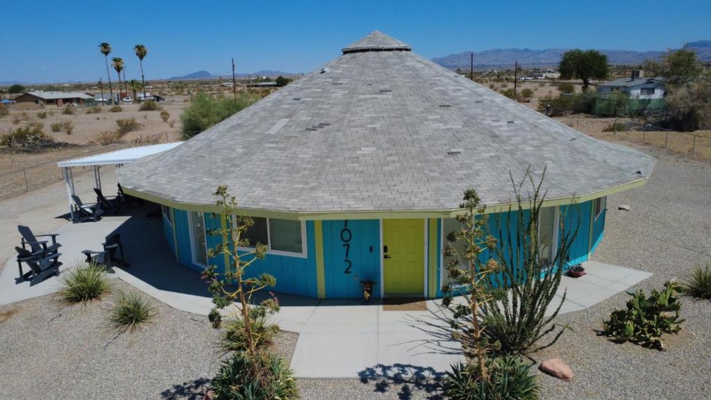 a small house with a thatched roof in the desert at The Round House in Parker