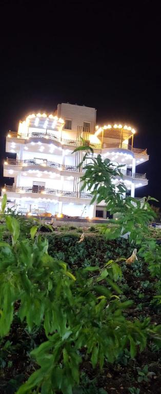 a large white building with lights on it at night at بيت مريم in Irjān