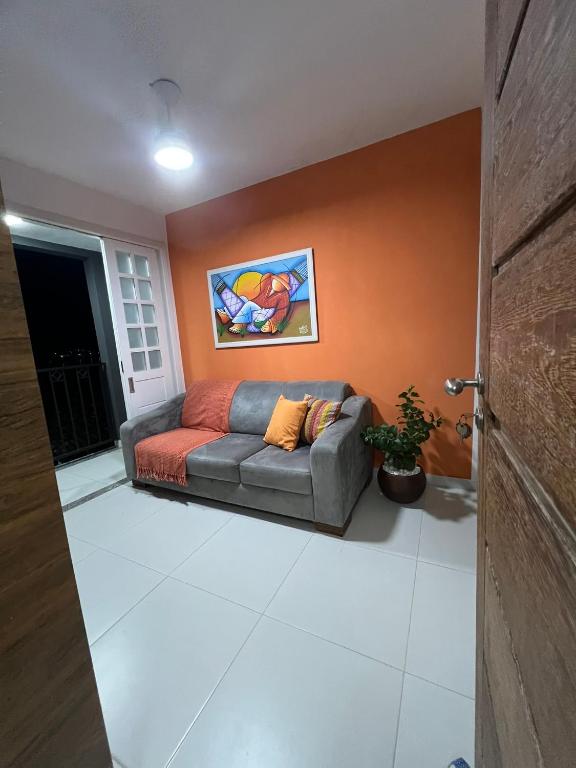 a couch in a living room with an orange wall at Aconchego do Caquende in Cachoeira
