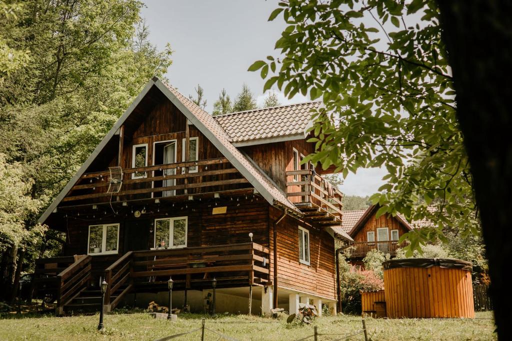 a large wooden house with a gambrel at Domki u Serowarki z Jacuzzi w cenie in Polańczyk