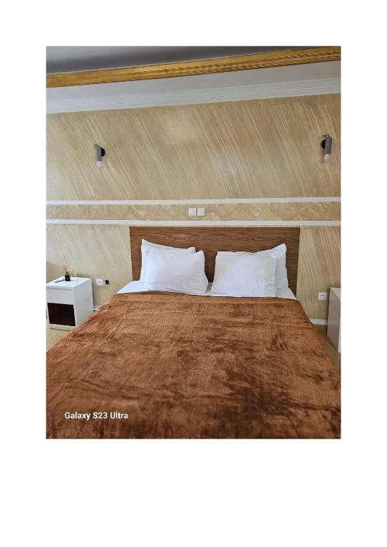 a bedroom with a large bed with a wooden headboard at Le MoniPol Hôtel in Franceville