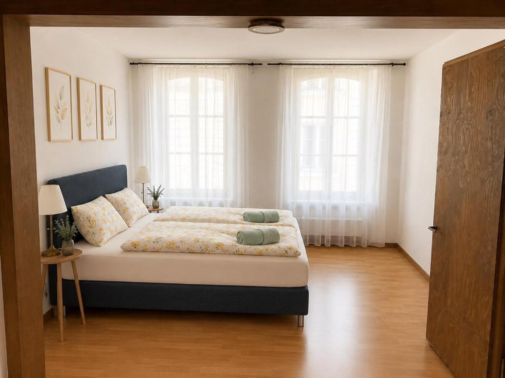 a bedroom with a large bed and two windows at Thun Arcades in Thun