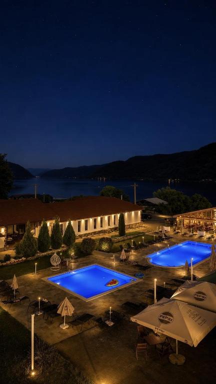 a group of three swimming pools at night at Clisura Dunarii - Pensiunea Casa Creta in Liborajdea