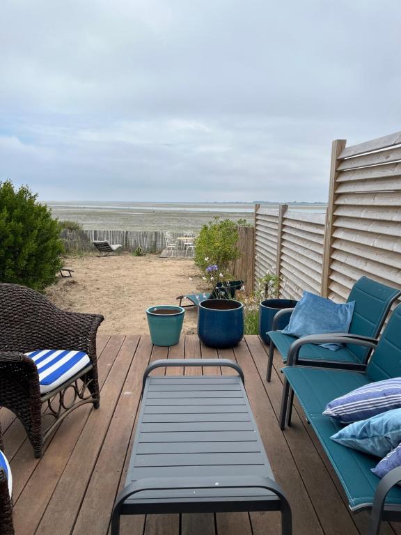 a deck with benches and chairs on the beach at L'escale les pieds dans l'eau in Barbâtre