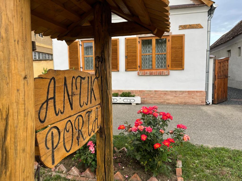 a sign in front of a house with flowers at Antik Porta-Hangulatos parasztház kerttel,borospincével és infraszaunával in Szakony