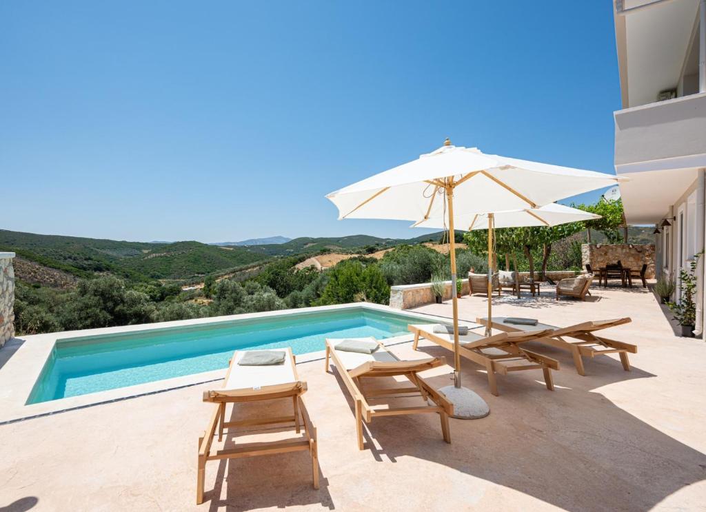 a villa with a swimming pool with chairs and an umbrella at CASA di FLORI in Epáno Flória