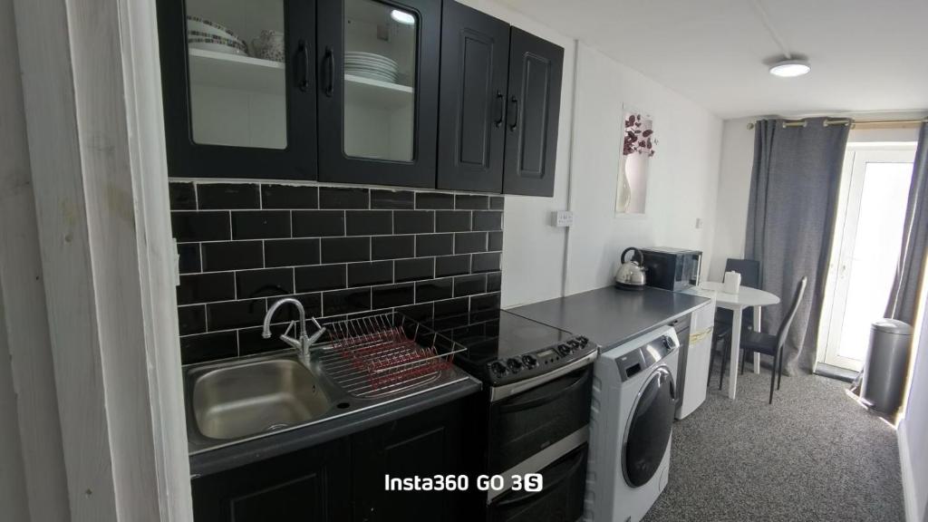 a kitchen with black cabinets and a sink and a stove at Abysplace SM in Kenton