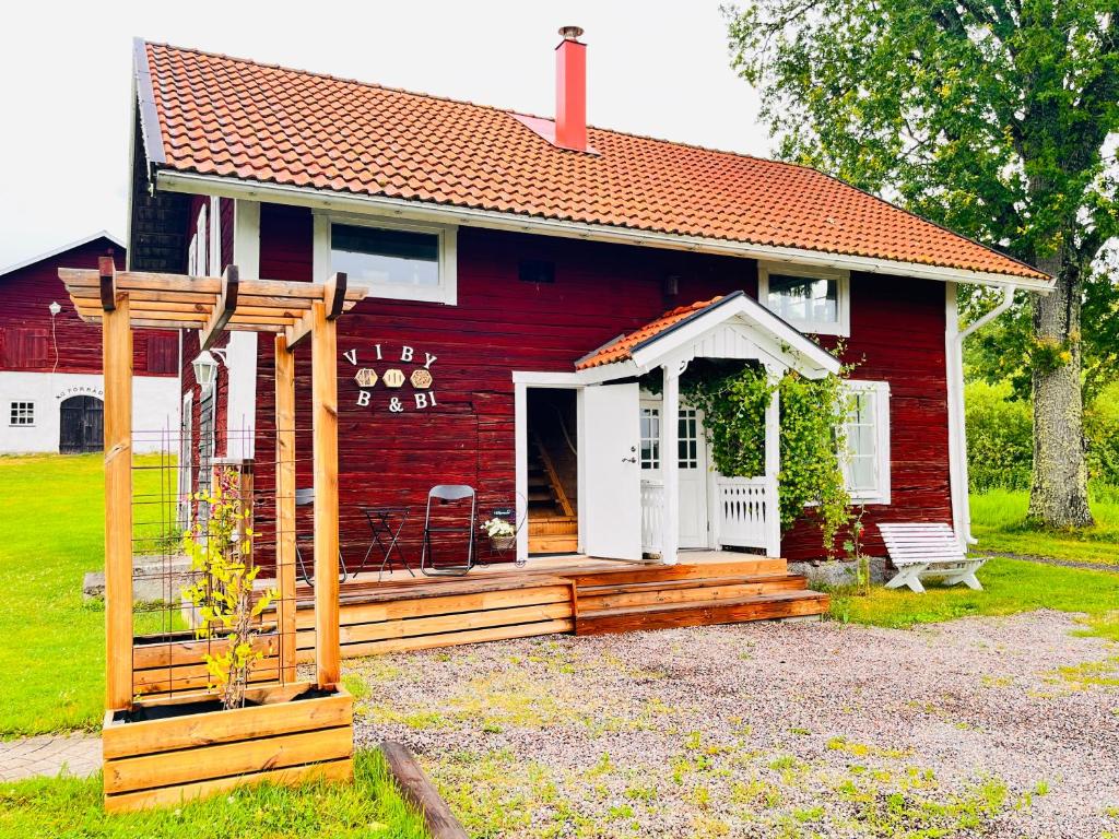 a red house with a white door and a porch at Rosengården - Viby B&Bi in Vretstorp
