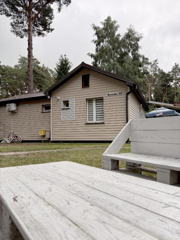a white bench sitting in front of a house at Barnaba Domki in Pobierowo