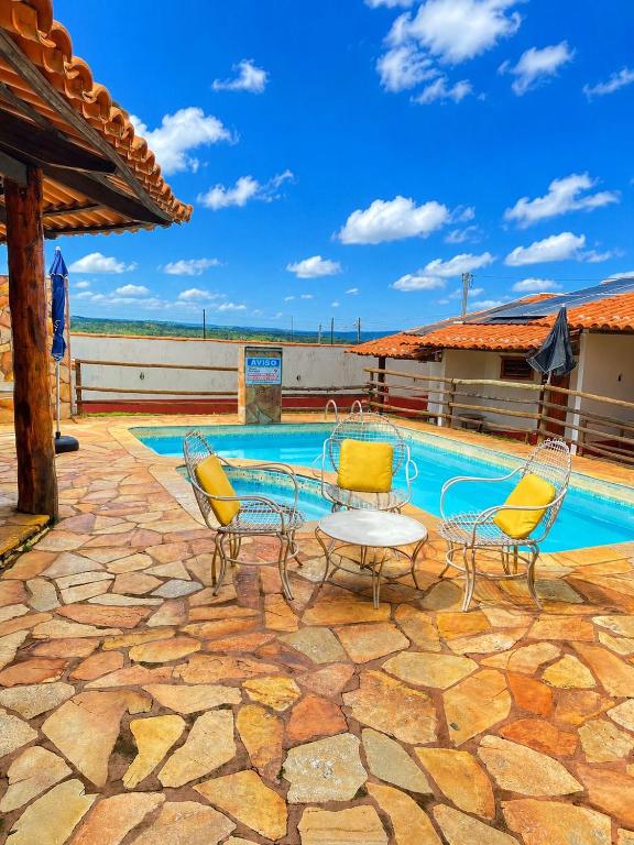 a patio with chairs and a table and a pool at Pousada Recanto da Serrinha in Corumbá de Goiás