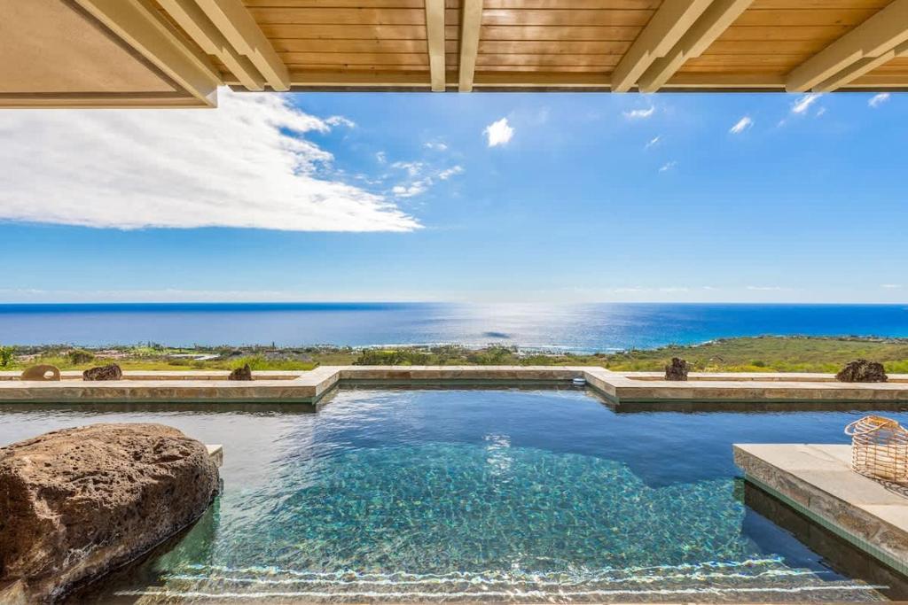 a swimming pool with a view of the ocean at Waterfall House - Hawaii in Kailua-Kona