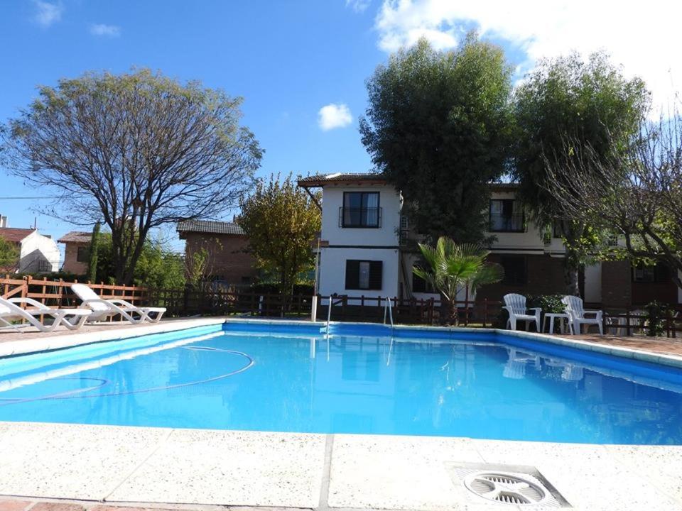 a large swimming pool in front of a house at Apart hotel Residencial El Puma in Mina Clavero