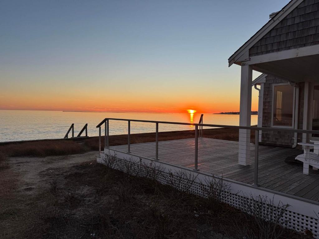 a house with a deck with the sunset in the background at Kalmus Park Retreat in Hyannis
