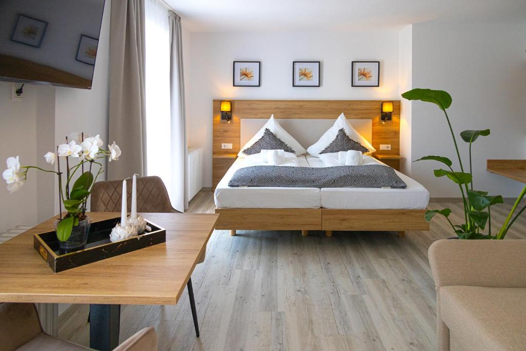 a bedroom with a bed and a wooden table at Hotel Ascona Bad Krozingen Frisch renoviert in bester Lage, nahe Autobahn, Kurpark und Vita Classica in Bad Krozingen