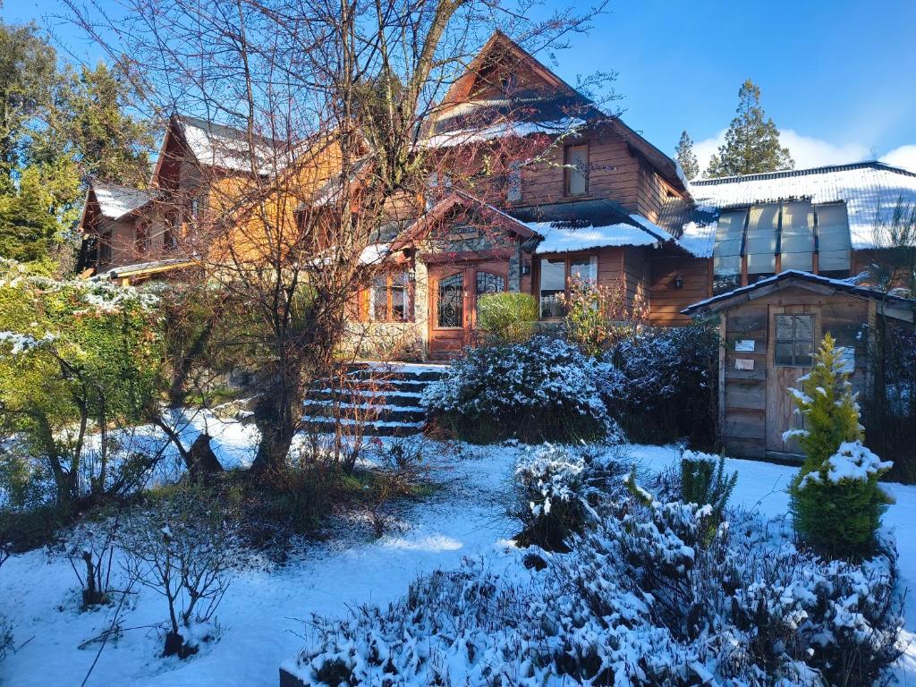 a wooden house with snow on the ground at Hostería Bajo Cero in Villa La Angostura