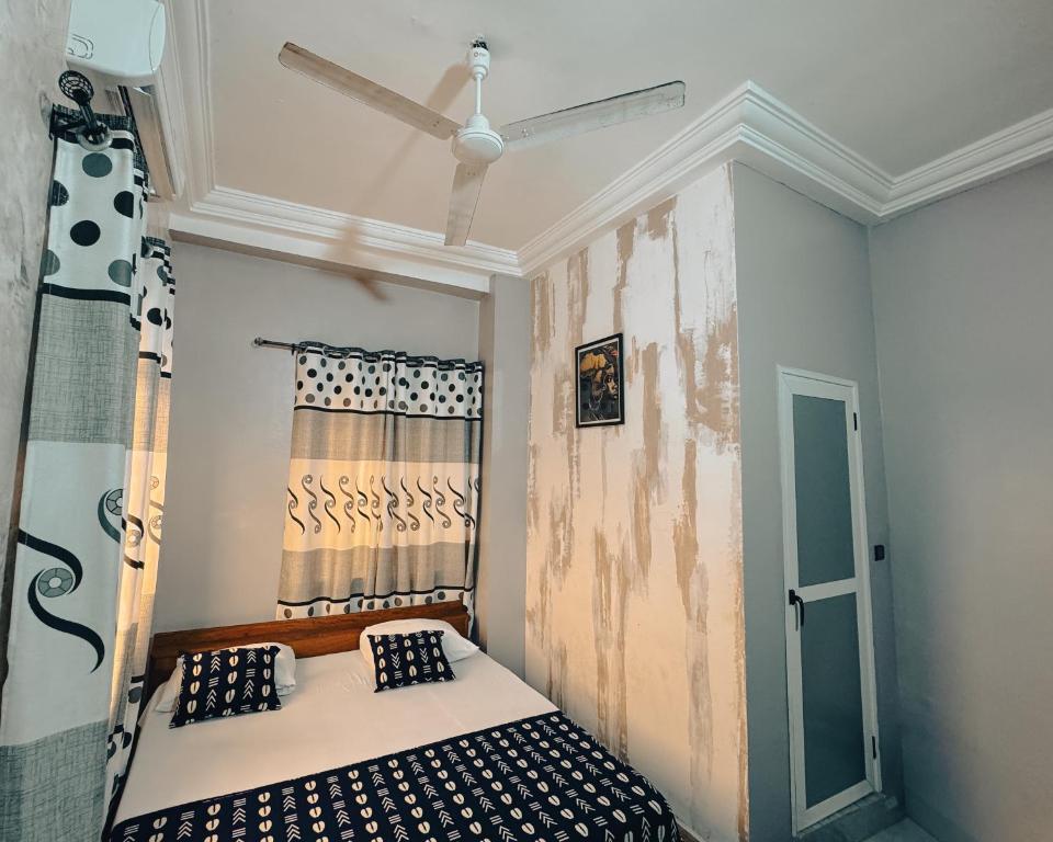 a room with a bed with a ceiling fan at Hôtel Merveille Lomé in Lomé