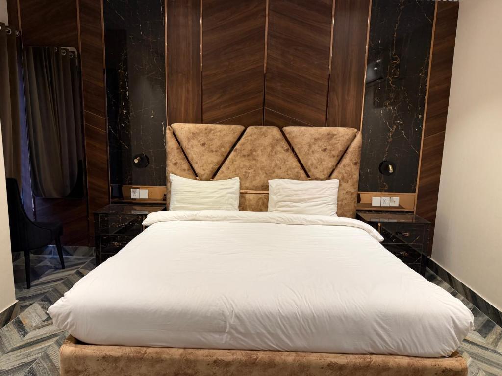 a bedroom with a large white bed with a headboard at The Horizon Hotel Islamabad in Islamabad
