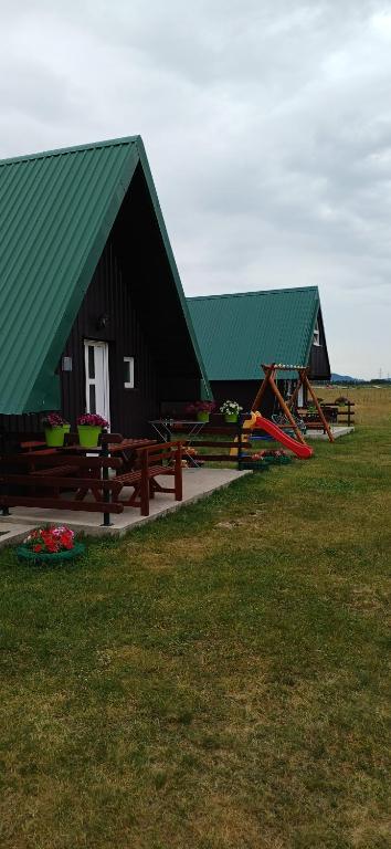 a building with green roofs and picnic tables in a field at Apartman Jegdic-Zabljak in Žabljak