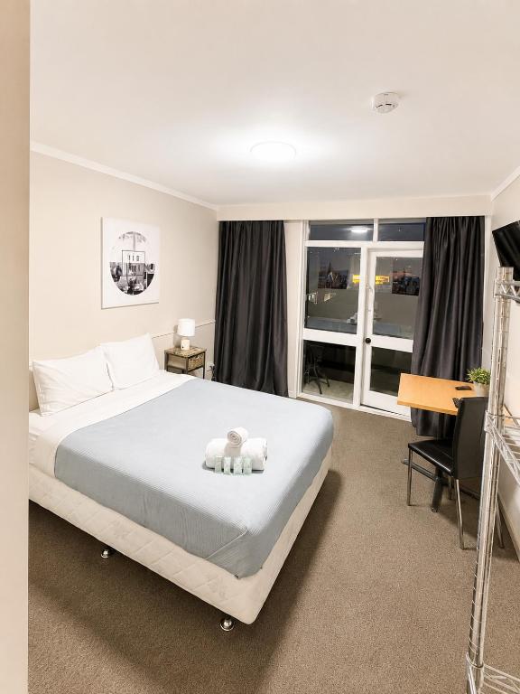 a bedroom with a large white bed and a desk at The Grand Wanganui in Whanganui