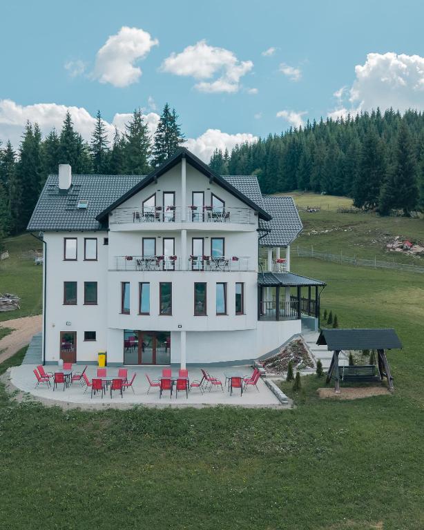 a large white house with red tables and chairs at VILA DE PE DEAL in Poiana Stampei