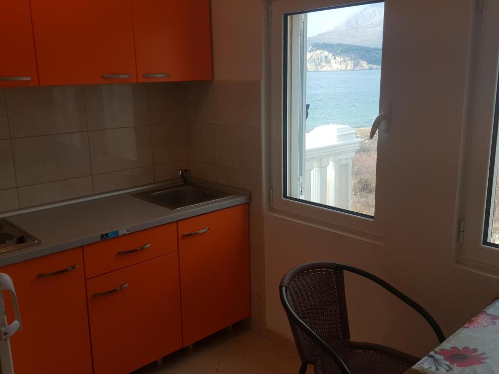 a kitchen with a window and a sink and a table at Buljarica Bay Apartments in Petrovac na Moru