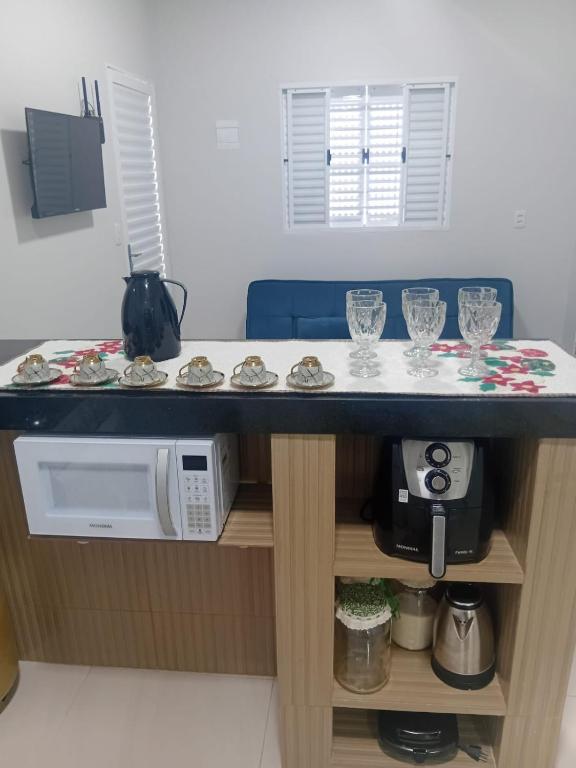 a kitchen counter with a microwave and glasses on it at Pousada Do Goiano in Manhã
