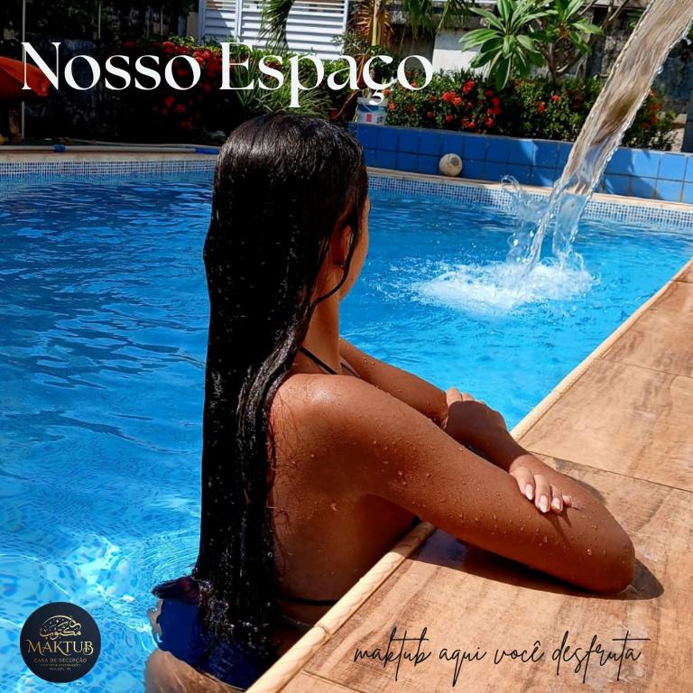 a young woman sitting in a swimming pool at Maktub Estadia e recepções in Paulista