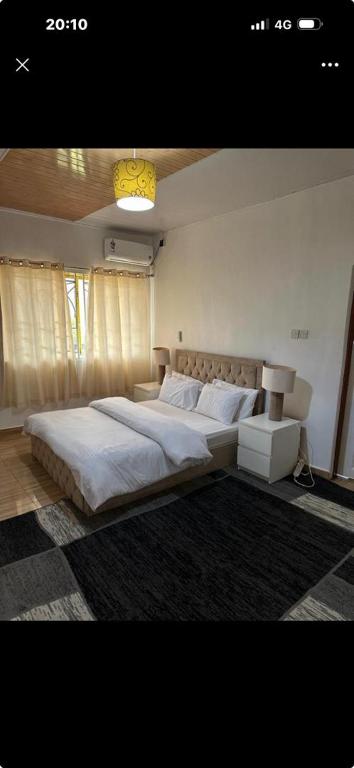 a bedroom with a large bed with white sheets at Rashlie apartment in Freetown